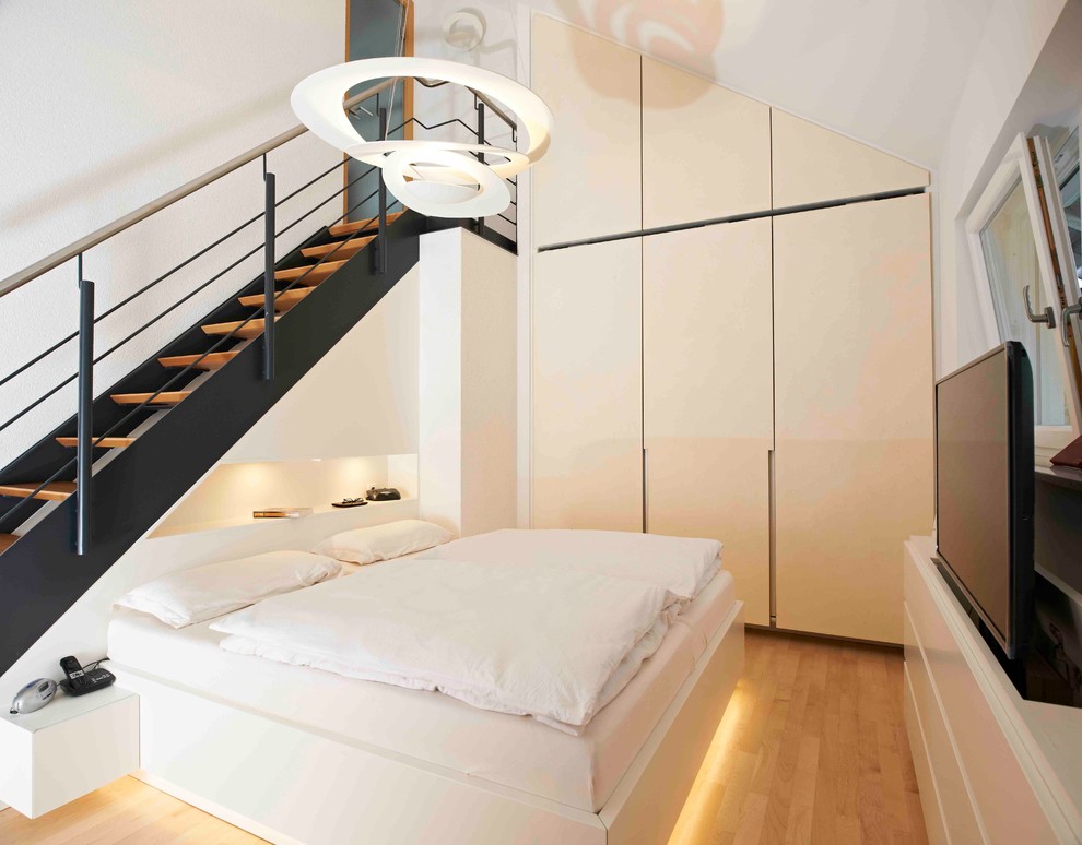 Foto de dormitorio principal contemporáneo de tamaño medio sin chimenea con paredes blancas, suelo de madera en tonos medios y suelo marrón
