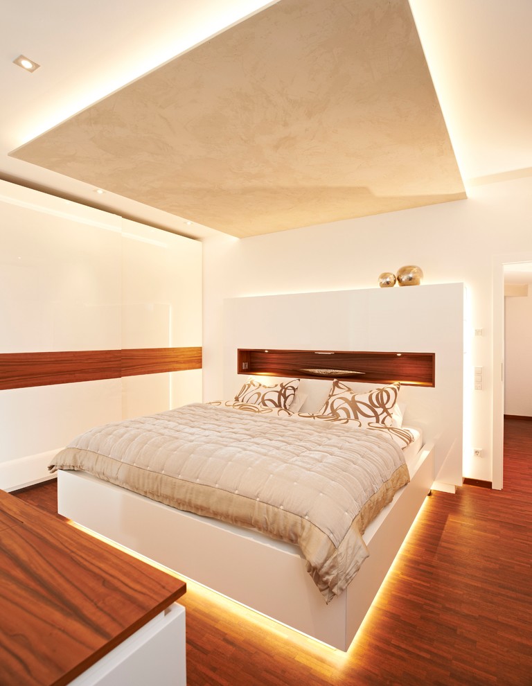 Cette photo montre une chambre parentale blanche et bois tendance de taille moyenne avec un mur blanc, un sol en bois brun, aucune cheminée et un sol marron.