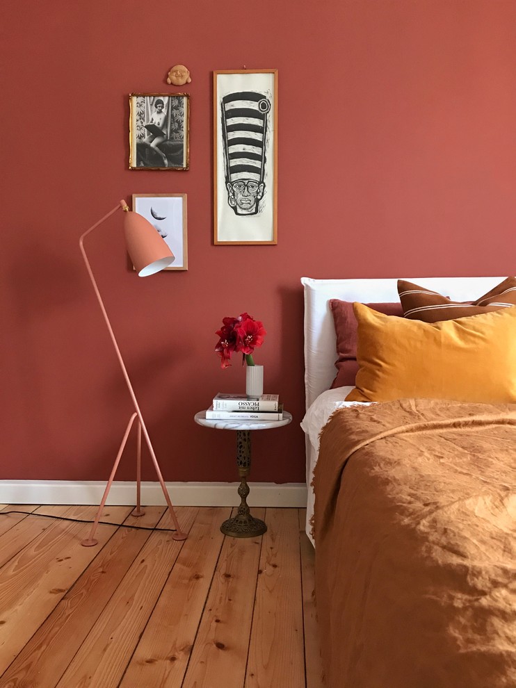 Idées déco pour une chambre parentale éclectique de taille moyenne avec un mur rouge, parquet clair et un sol marron.