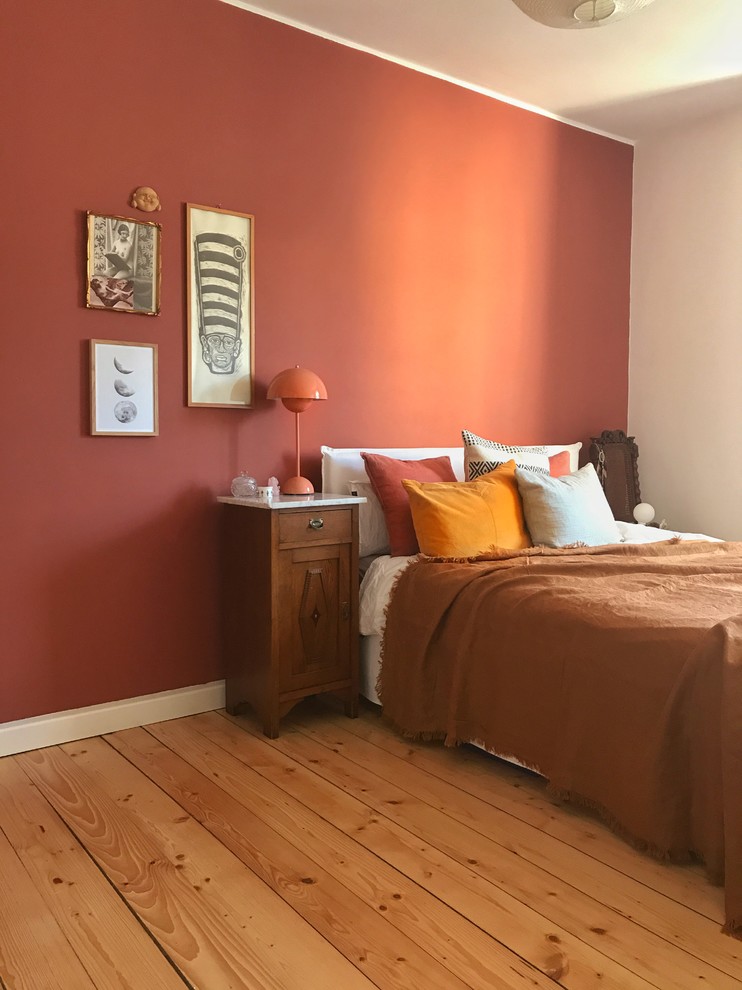 Mittelgroßes Stilmix Hauptschlafzimmer mit roter Wandfarbe, hellem Holzboden und braunem Boden in Berlin