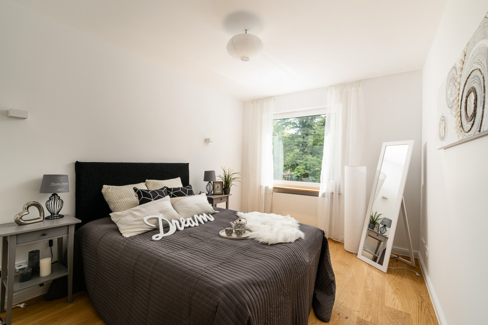Mittelgroßes Klassisches Schlafzimmer mit weißer Wandfarbe, braunem Holzboden und braunem Boden in München
