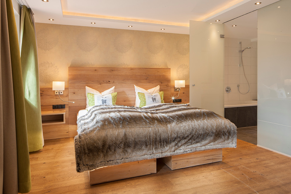 Diseño de dormitorio principal contemporáneo grande sin chimenea con paredes beige y suelo de madera en tonos medios