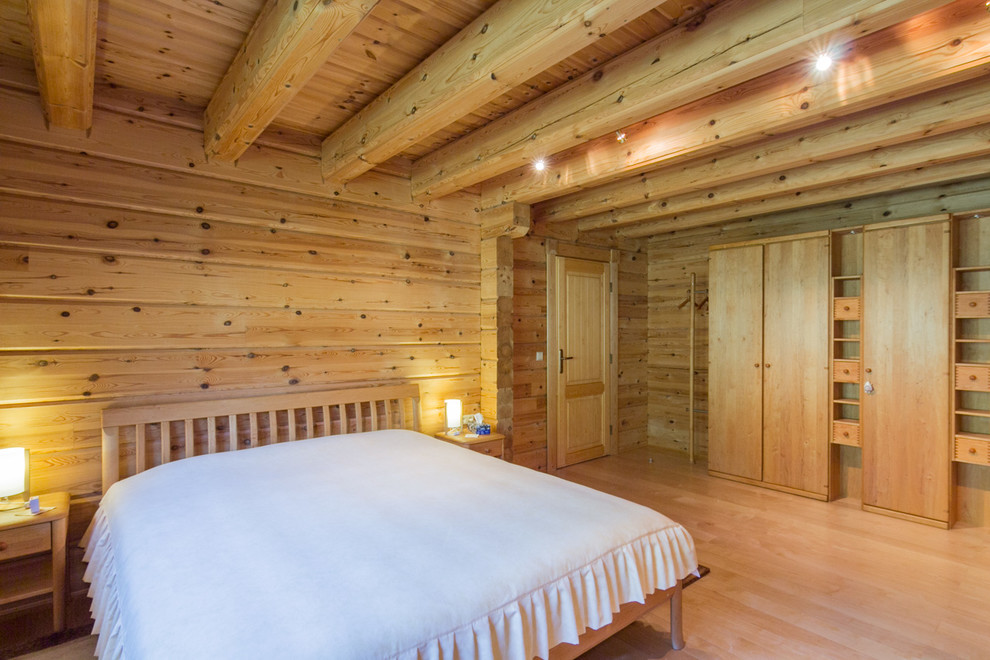Diseño de dormitorio principal rústico grande sin chimenea con paredes marrones y suelo de madera clara