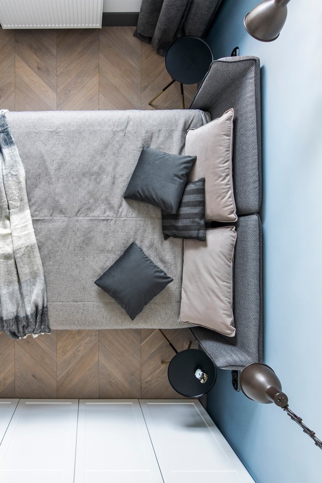 Kleines Nordisches Schlafzimmer mit blauer Wandfarbe, braunem Holzboden und braunem Boden in Stuttgart