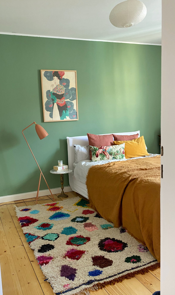 Modelo de dormitorio principal ecléctico de tamaño medio con paredes verdes, suelo de madera clara y suelo marrón