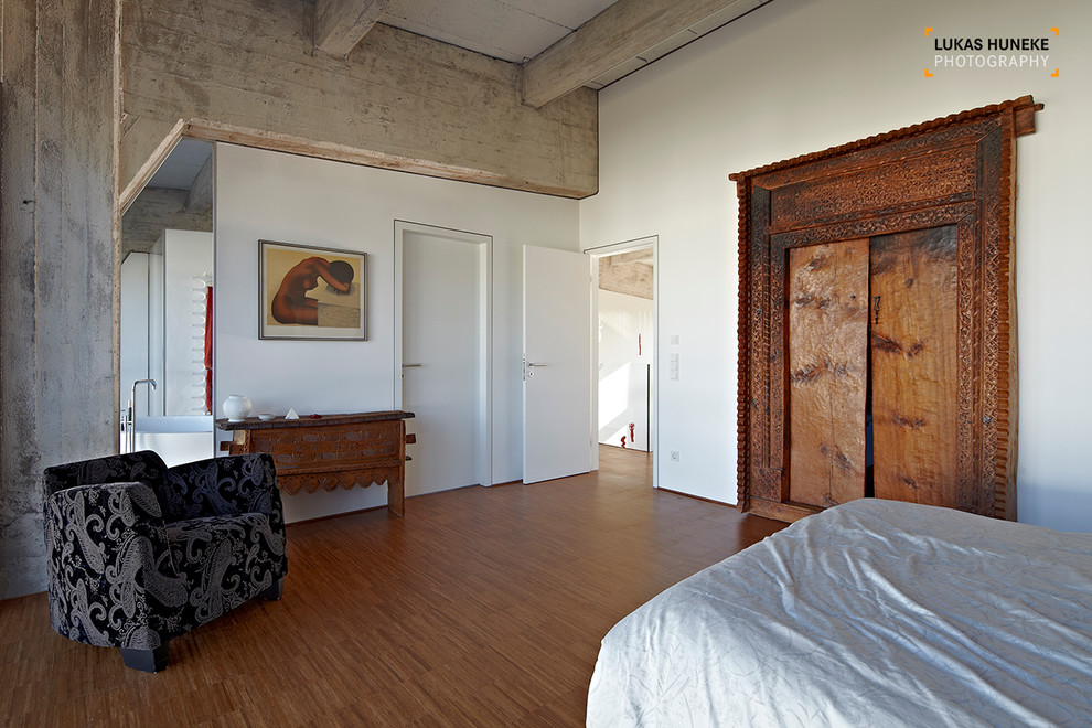 Ispirazione per una camera da letto industriale di medie dimensioni con pareti bianche e pavimento in legno massello medio