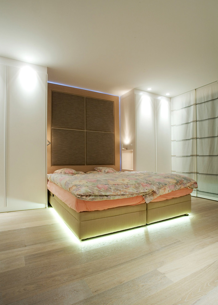 Imagen de dormitorio principal contemporáneo de tamaño medio sin chimenea con paredes blancas, suelo de madera en tonos medios y suelo beige