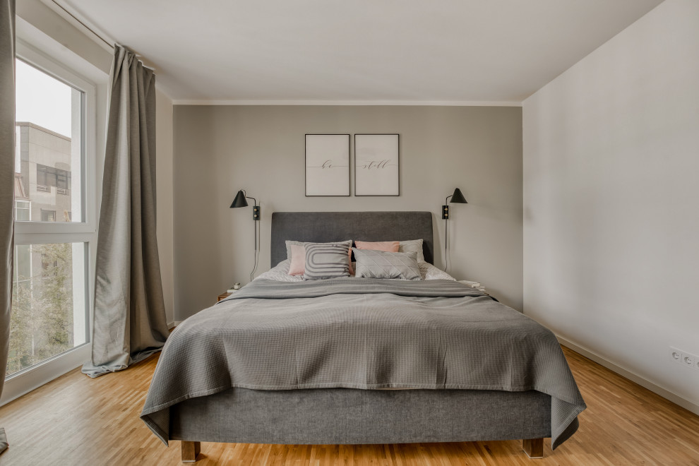 This is an example of a medium sized scandi bedroom in Hamburg with grey walls, medium hardwood flooring and brown floors.