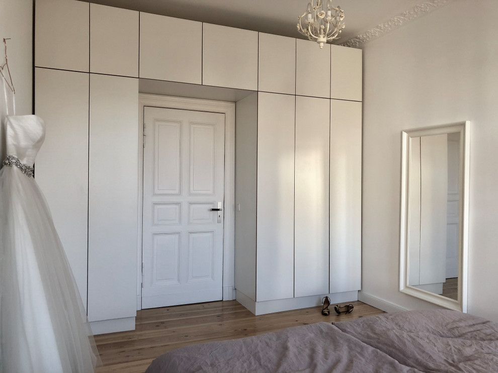 Ispirazione per una piccola camera matrimoniale minimal con pareti bianche, parquet chiaro e pavimento marrone