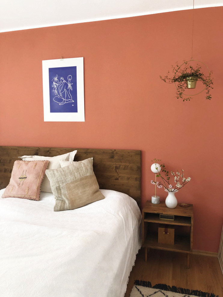 На фото: хозяйская спальня среднего размера в стиле модернизм с оранжевыми стенами, светлым паркетным полом и коричневым полом без камина с