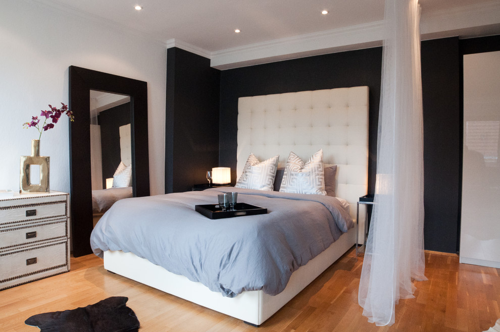 This is an example of a large contemporary master bedroom in Berlin with black walls, medium hardwood flooring and no fireplace.