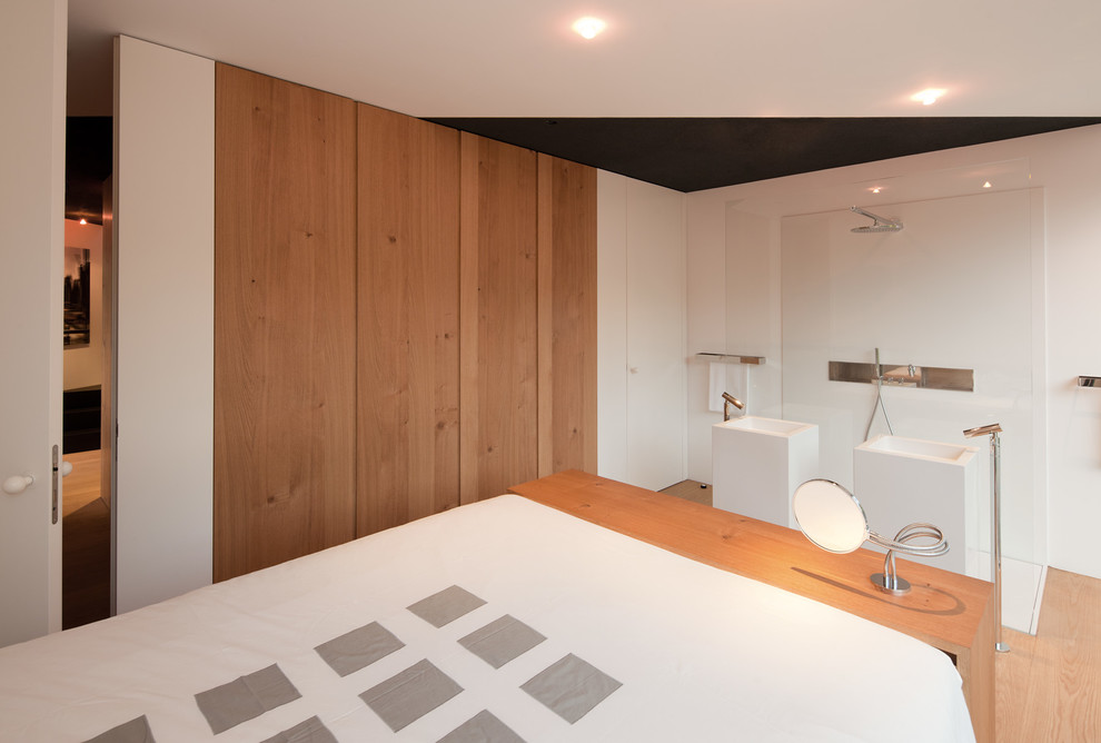 Imagen de dormitorio principal contemporáneo de tamaño medio con paredes blancas, suelo de madera clara y suelo marrón