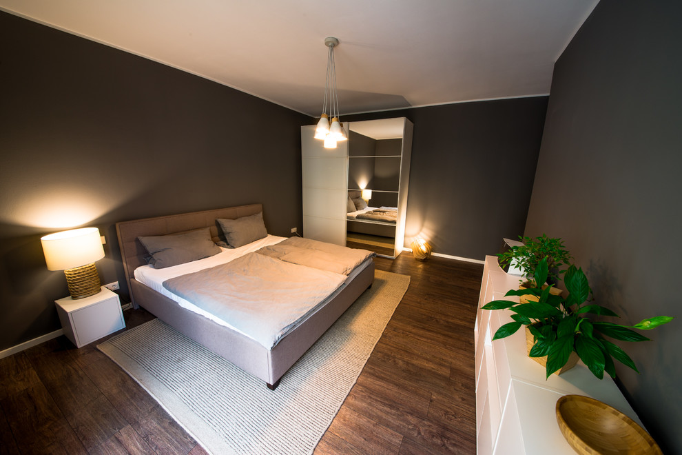 Ejemplo de dormitorio principal contemporáneo de tamaño medio sin chimenea con paredes negras, suelo de madera en tonos medios y suelo marrón