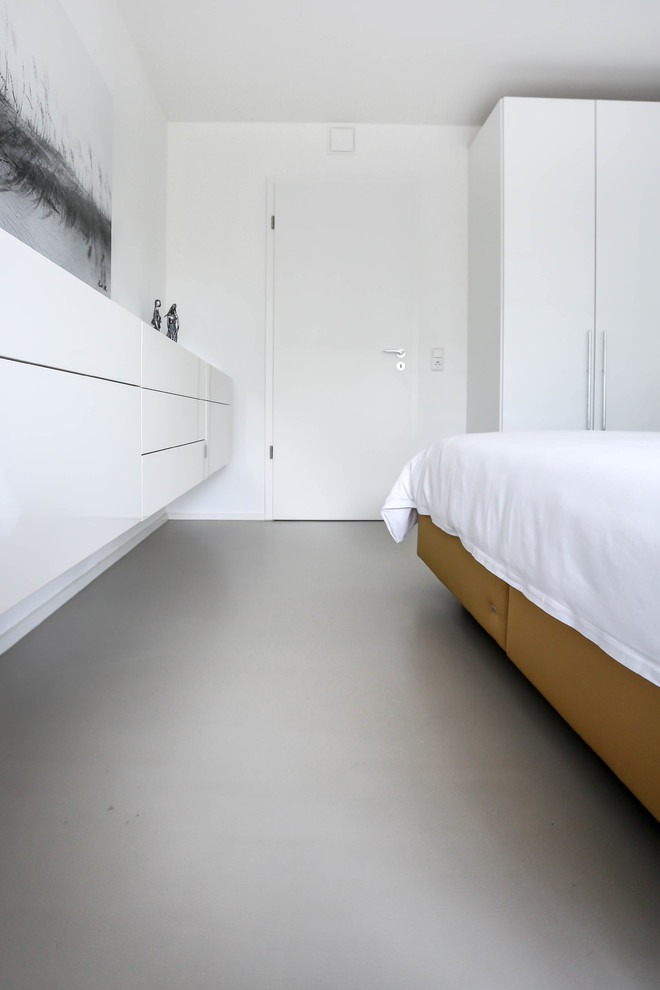 Esempio di una camera da letto minimalista con pavimento in cemento