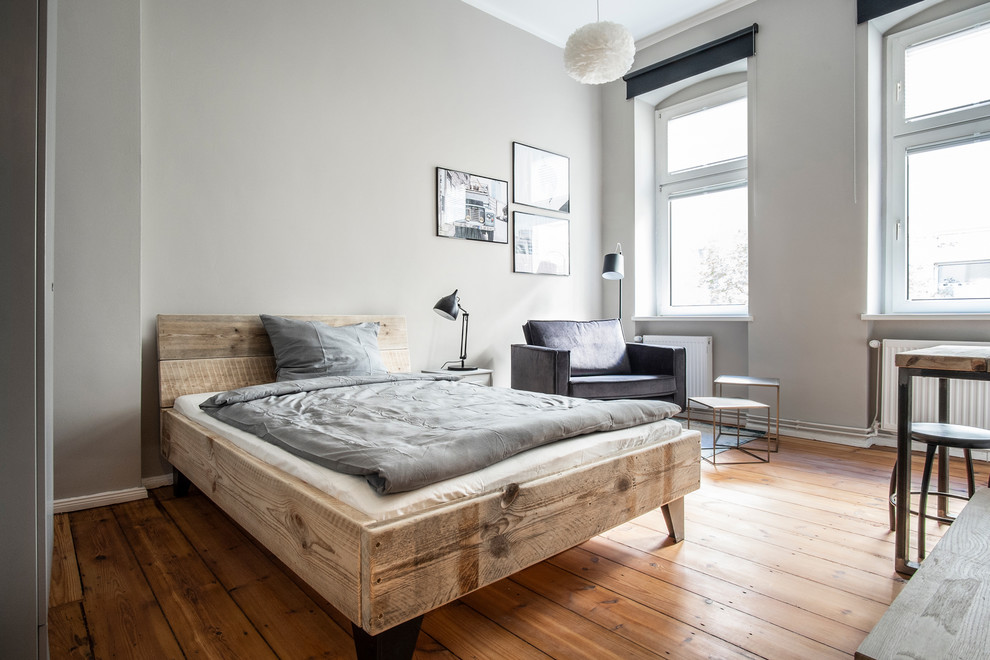 Mittelgroßes Modernes Hauptschlafzimmer ohne Kamin mit grauer Wandfarbe, braunem Holzboden und braunem Boden in Berlin