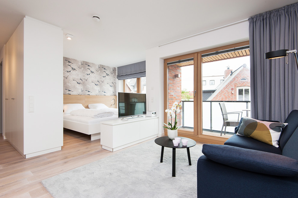 Diseño de dormitorio nórdico pequeño sin chimenea con paredes blancas y suelo de madera en tonos medios