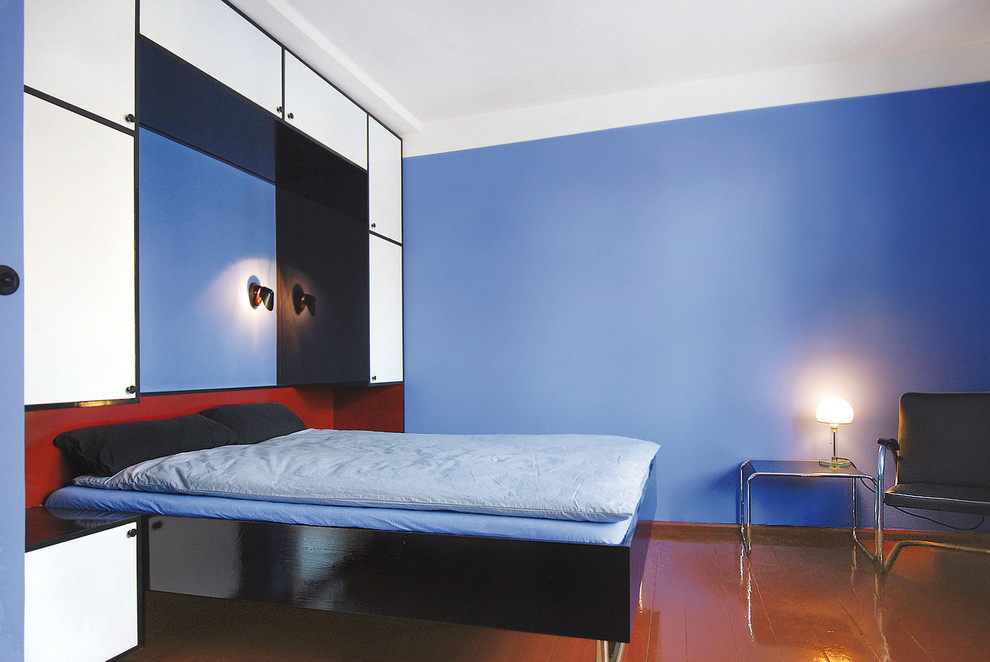 Ispirazione per una camera da letto minimalista con pareti blu e pavimento in legno verniciato