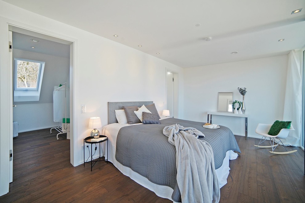 Modelo de dormitorio principal contemporáneo de tamaño medio sin chimenea con paredes blancas, suelo de madera en tonos medios y suelo marrón