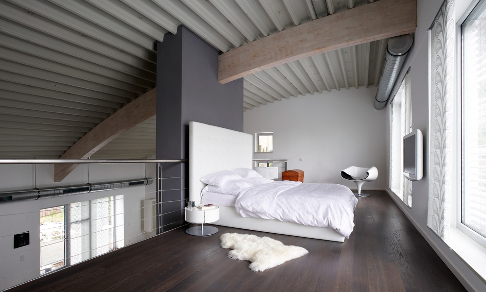 Geräumiges Industrial Schlafzimmer im Dachboden ohne Kamin, im Loft-Style mit dunklem Holzboden, weißer Wandfarbe, verputzter Kaminumrandung und braunem Boden in Sonstige