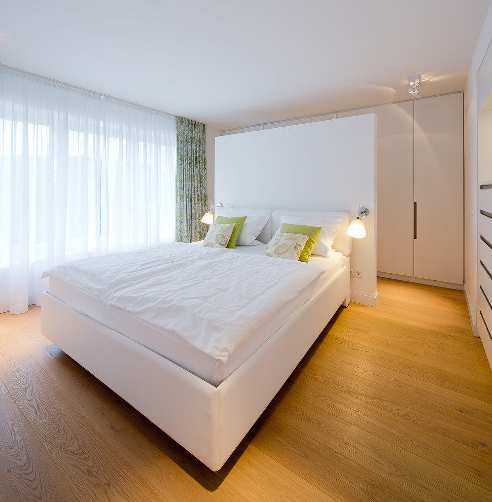 デュッセルドルフにある広いコンテンポラリースタイルのおしゃれな主寝室 (白い壁、無垢フローリング、暖炉なし) のレイアウト