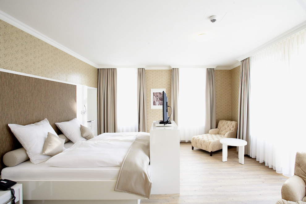 Foto de dormitorio principal y televisión tradicional grande sin chimenea con paredes beige y suelo de madera clara