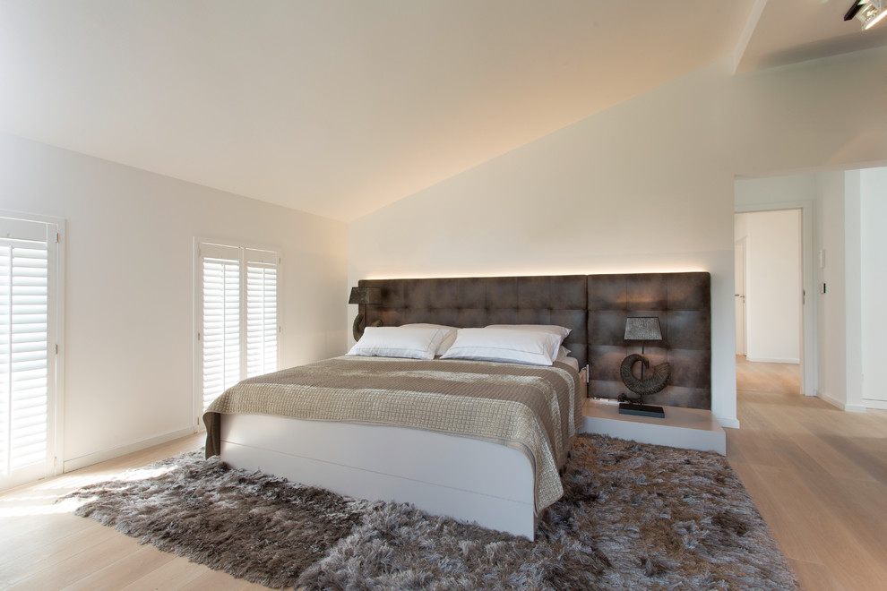 Diseño de dormitorio principal actual de tamaño medio con paredes blancas y suelo de madera clara