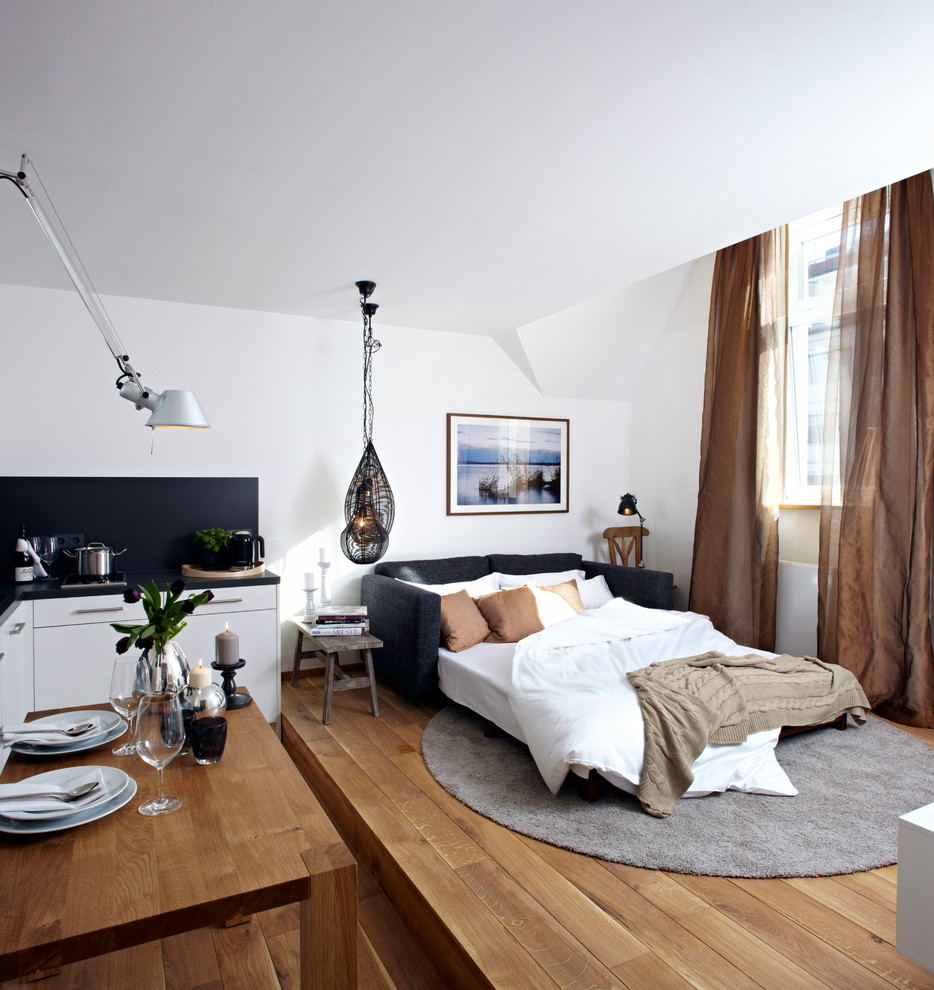 Immagine di una camera da letto design di medie dimensioni con pareti bianche, pavimento in legno massello medio e nessun camino