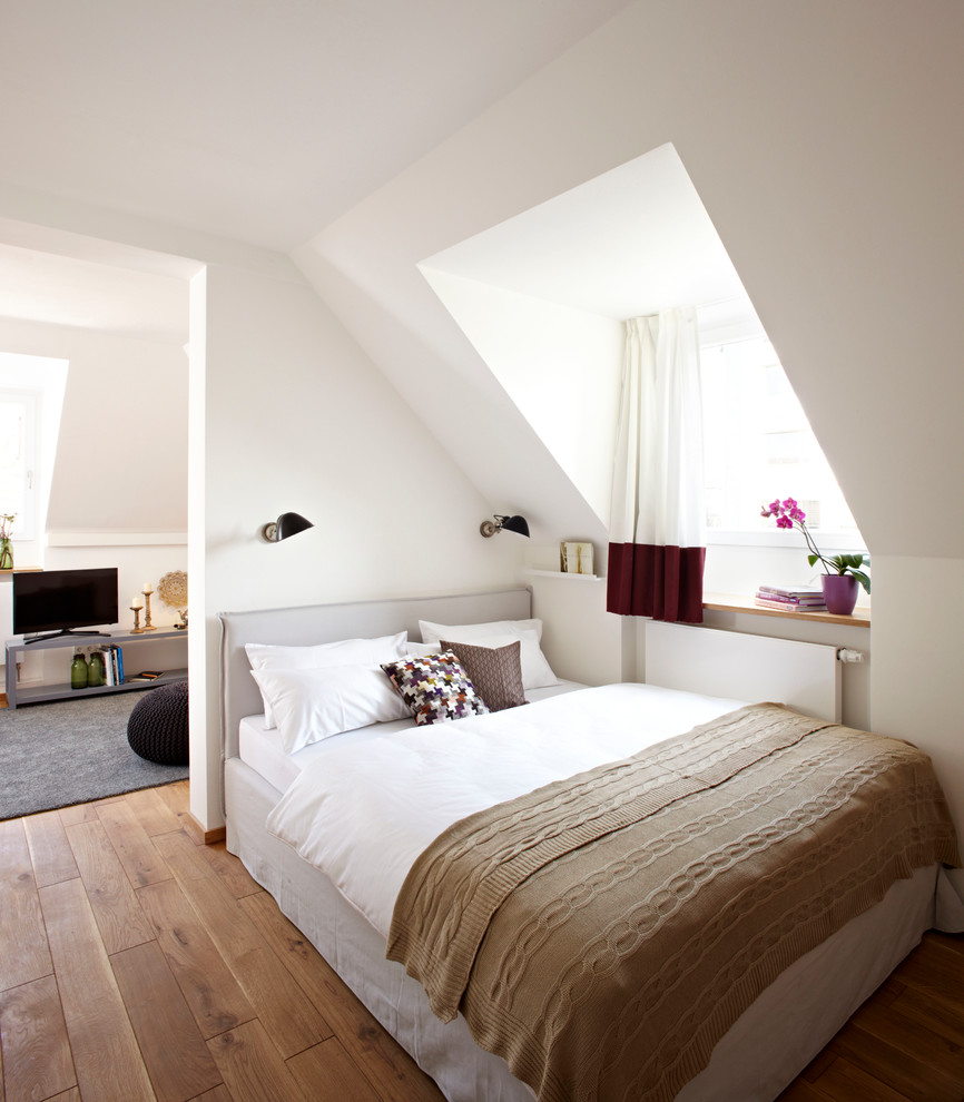 Mittelgroßes Skandinavisches Schlafzimmer ohne Kamin mit weißer Wandfarbe und braunem Holzboden in München