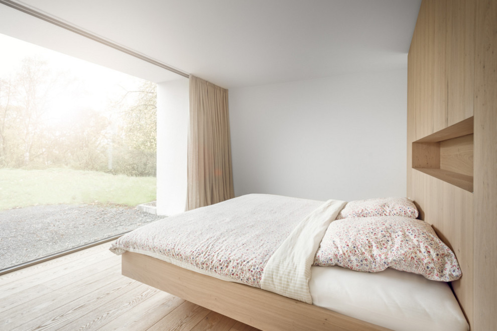 Immagine di una camera da letto contemporanea di medie dimensioni con pareti bianche, parquet chiaro e nessun camino