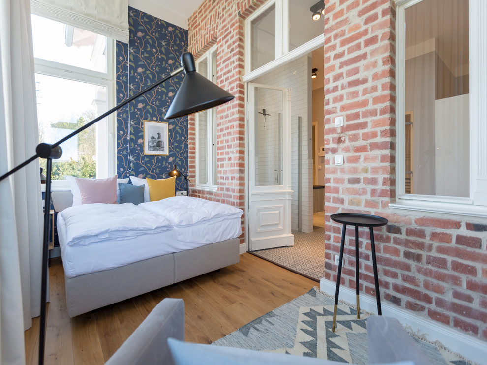 Cette photo montre une chambre parentale tendance de taille moyenne avec un mur bleu, un sol en bois brun, aucune cheminée et un sol marron.