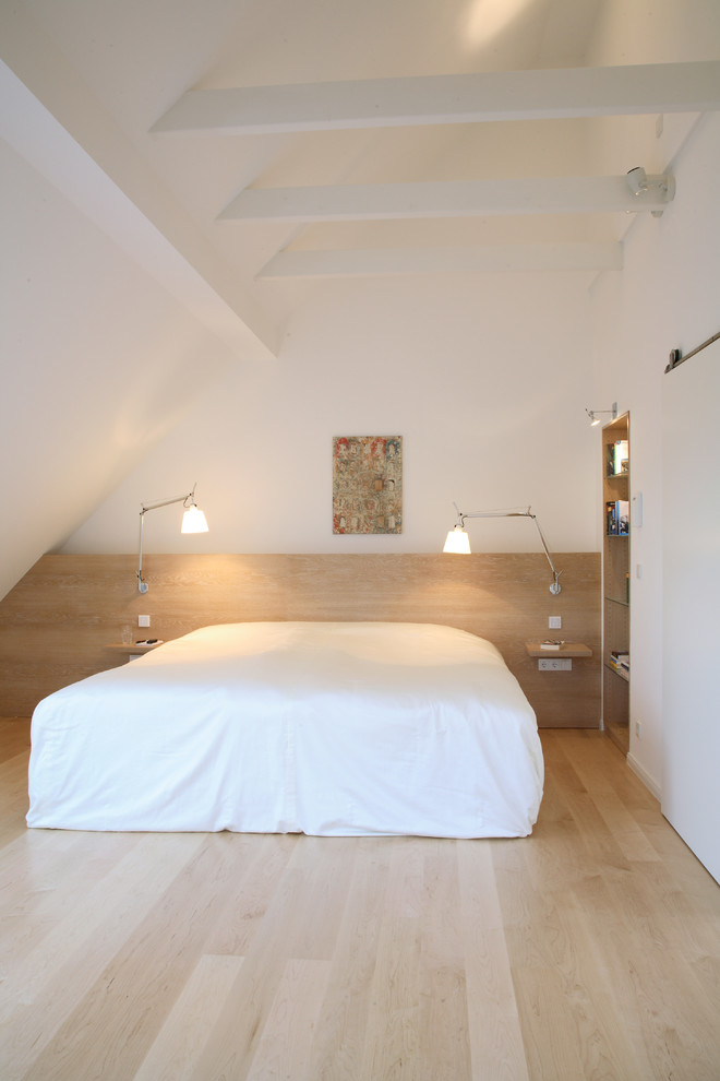 Mittelgroßes Modernes Schlafzimmer ohne Kamin mit weißer Wandfarbe und hellem Holzboden in Köln