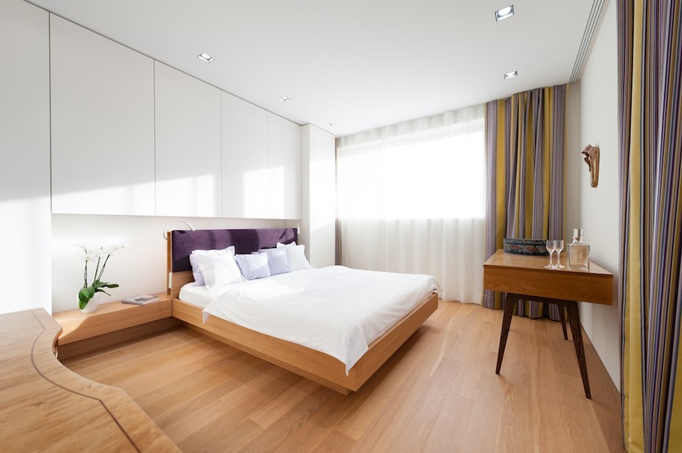 Mittelgroßes Modernes Hauptschlafzimmer ohne Kamin mit weißer Wandfarbe und braunem Holzboden in München