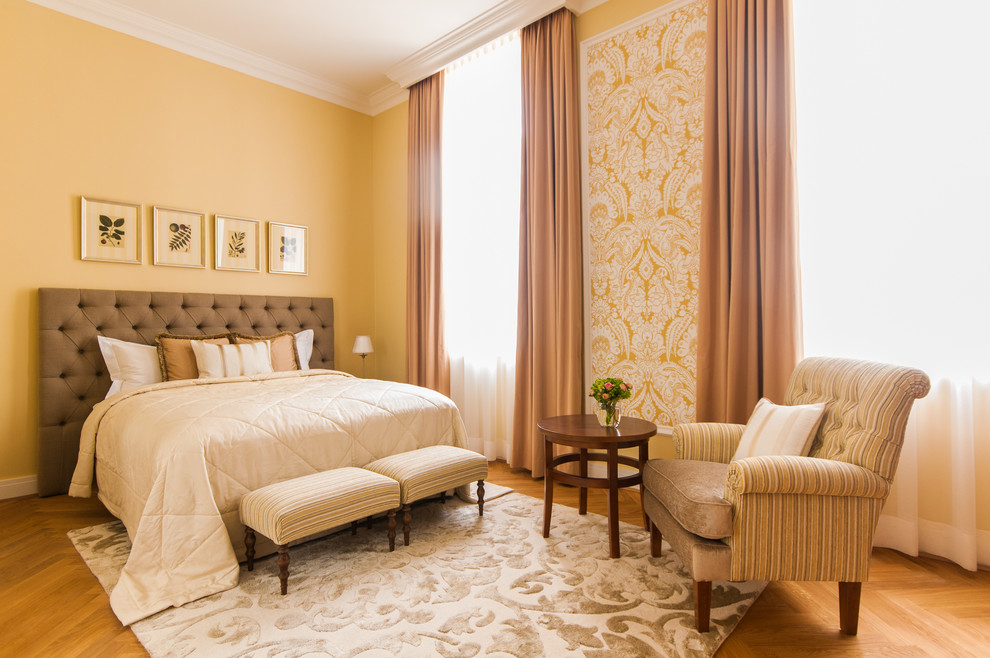 他の地域にある広いトラディショナルスタイルのおしゃれな主寝室 (黄色い壁、淡色無垢フローリング、暖炉なし、アクセントウォール)