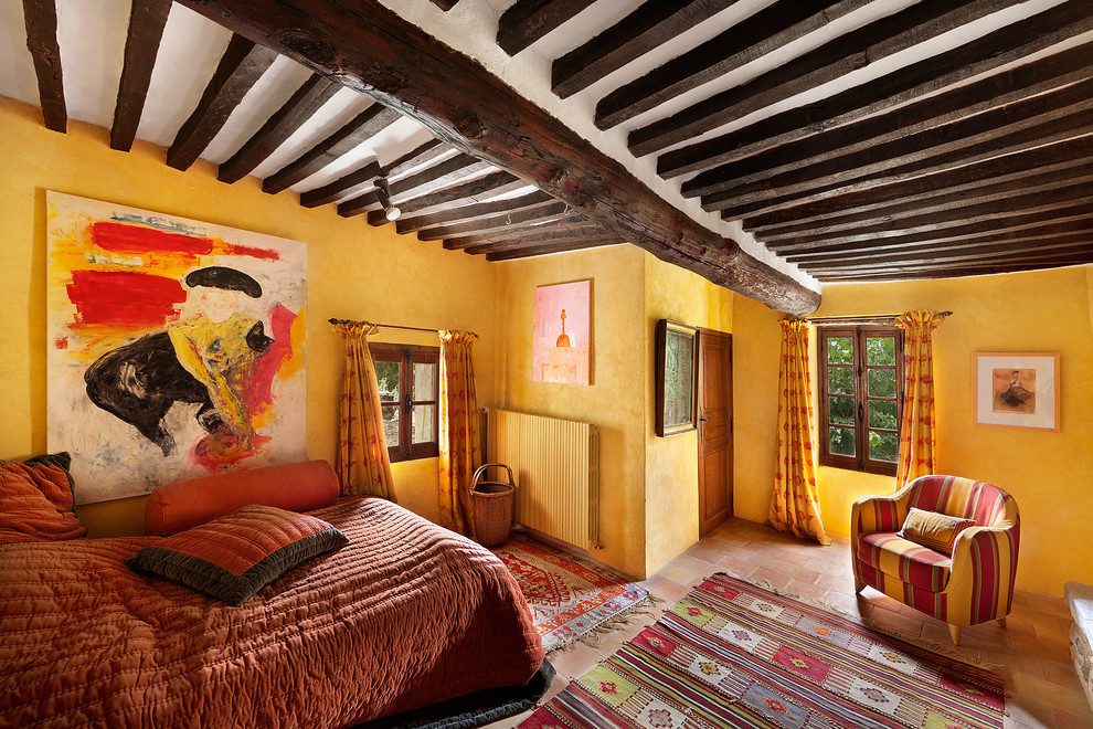 Exemple d'une chambre parentale méditerranéenne de taille moyenne avec un mur jaune, tomettes au sol et aucune cheminée.