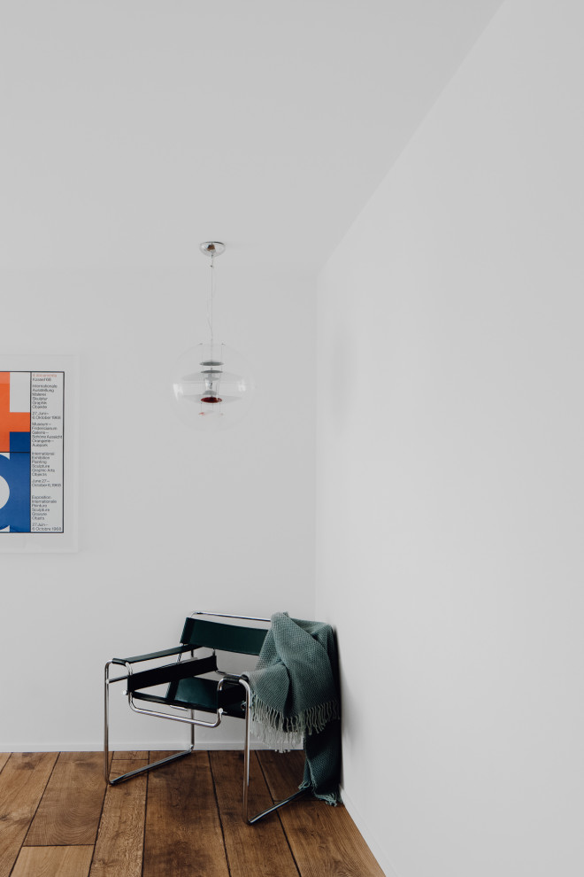 На фото: большая спальня в стиле модернизм с белыми стенами, темным паркетным полом, печью-буржуйкой, фасадом камина из штукатурки и коричневым полом с