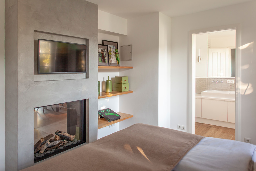 Идея дизайна: гостевая спальня среднего размера, (комната для гостей) в современном стиле с белыми стенами, деревянным полом, двусторонним камином и фасадом камина из бетона