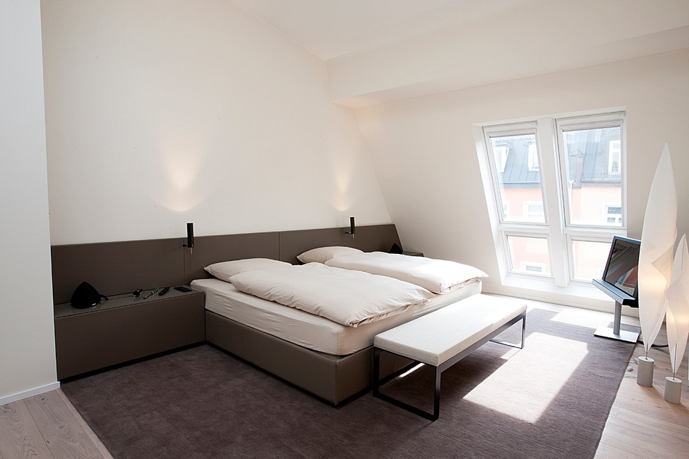 Foto de dormitorio principal y televisión contemporáneo de tamaño medio sin chimenea con paredes blancas, suelo de madera en tonos medios y techo inclinado