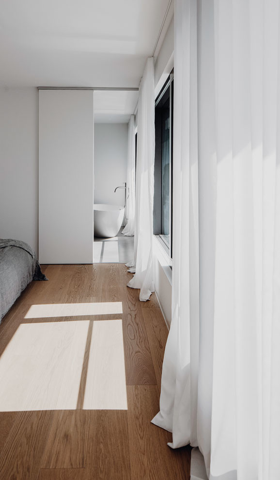 Foto di una camera da letto stile loft moderna di medie dimensioni con pareti bianche, parquet chiaro e pavimento marrone