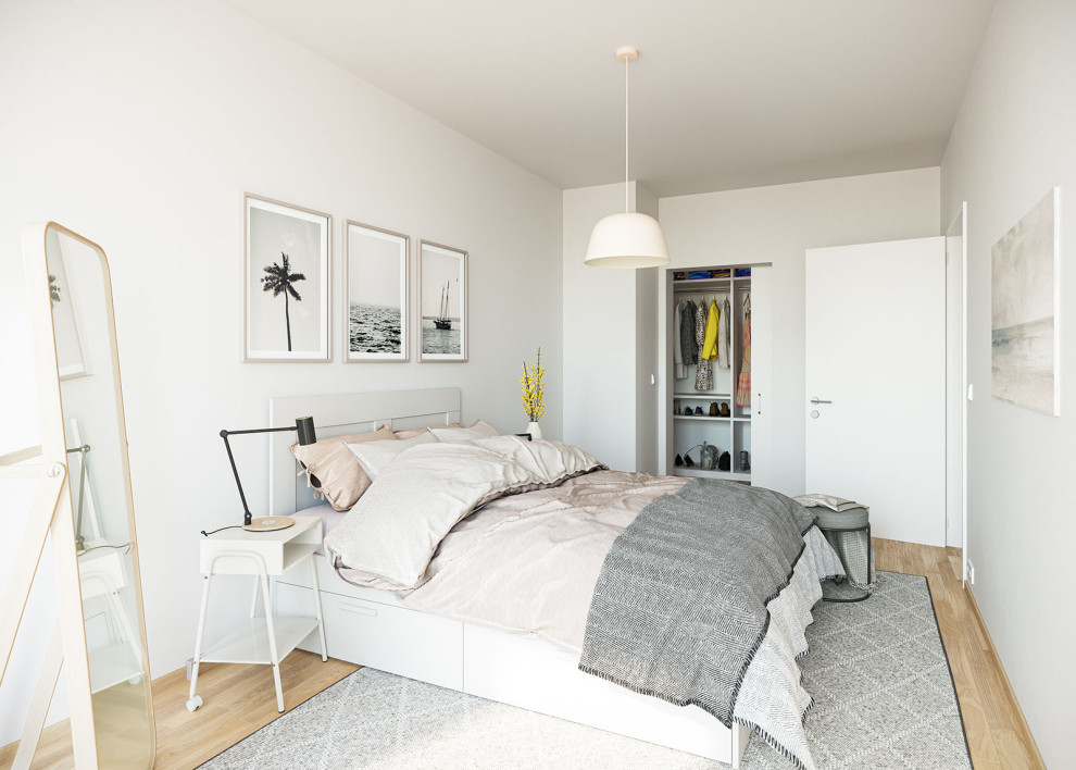 Imagen de dormitorio principal nórdico de tamaño medio con paredes blancas, suelo laminado y suelo marrón