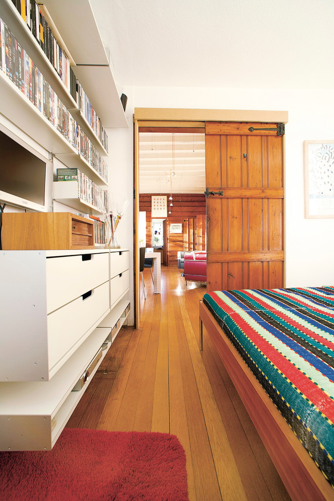 Diseño de dormitorio actual sin chimenea con paredes blancas y suelo de madera en tonos medios