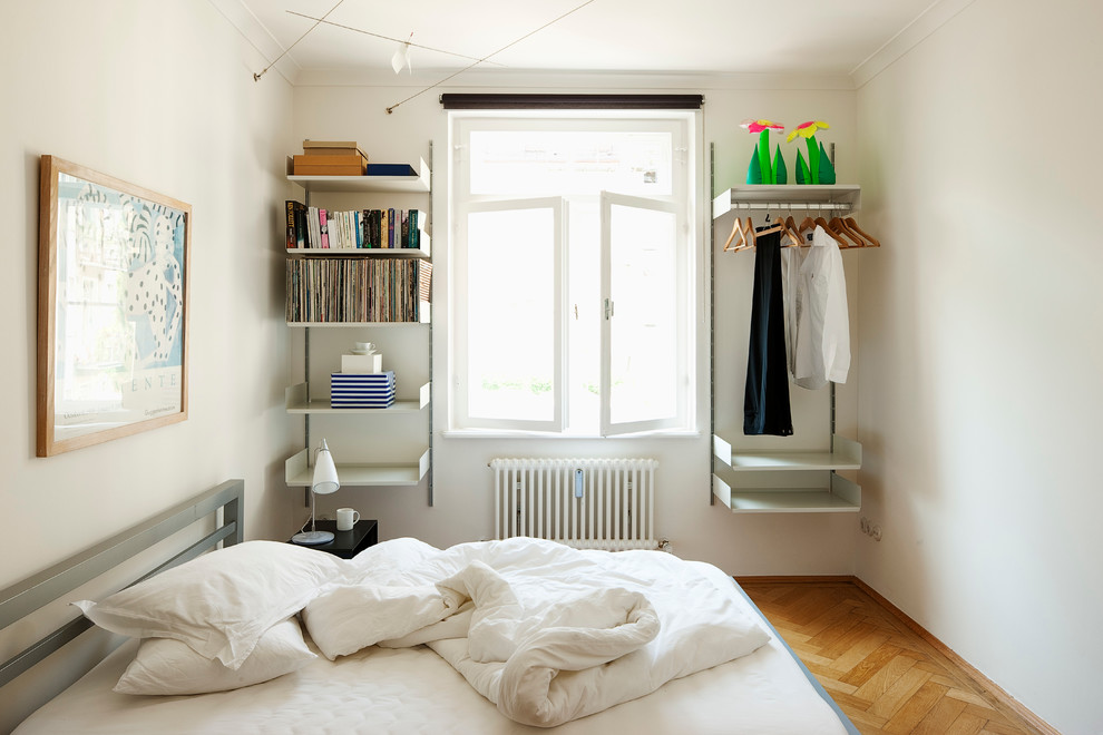 Bild på ett litet funkis sovrum, med vita väggar och mellanmörkt trägolv