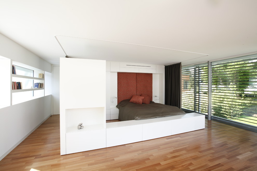 Réalisation d'une très grande chambre d'amis minimaliste avec un mur blanc, un sol en bois brun et aucune cheminée.