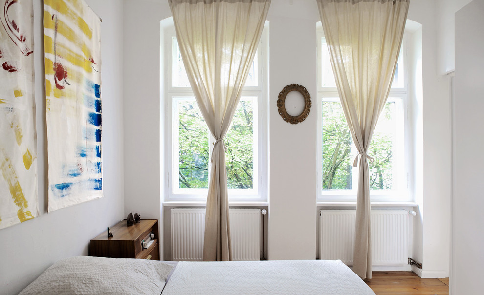 Mittelgroßes Modernes Schlafzimmer ohne Kamin mit weißer Wandfarbe und braunem Holzboden in Berlin
