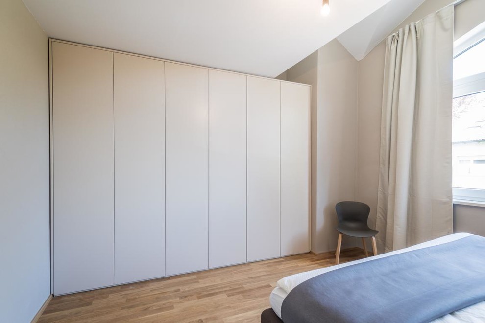 Modernes Hauptschlafzimmer mit beiger Wandfarbe, braunem Holzboden und braunem Boden in München