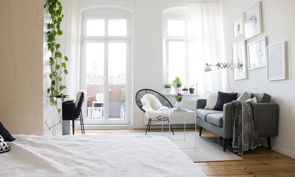 Kleines Nordisches Schlafzimmer ohne Kamin mit weißer Wandfarbe und braunem Holzboden in Berlin