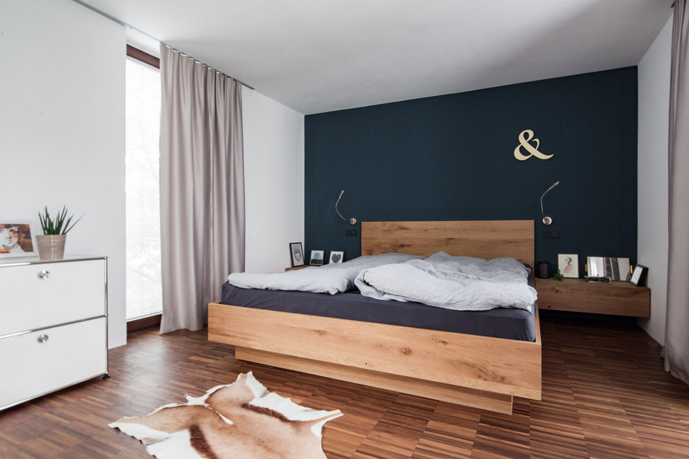 Idée de décoration pour une chambre parentale nordique de taille moyenne avec un mur bleu.