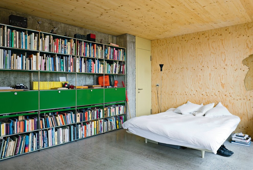 This is an example of a large urban master bedroom in Berlin with concrete flooring, no fireplace and grey walls.