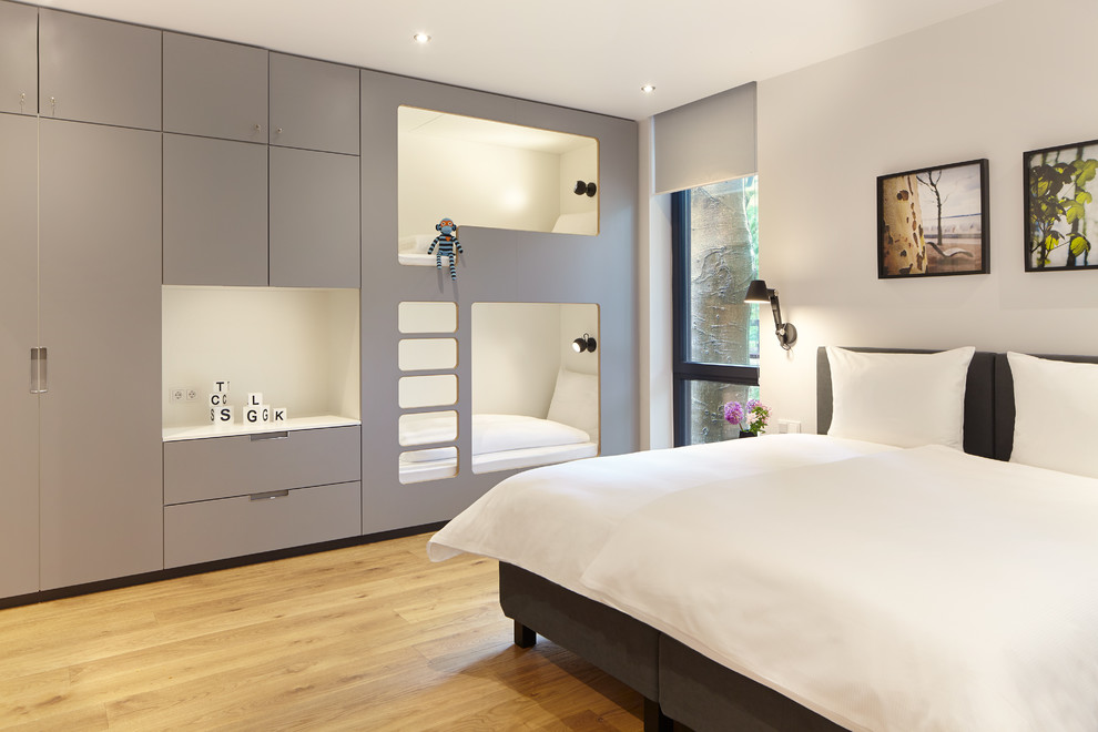 中くらいなコンテンポラリースタイルのおしゃれな客用寝室 (白い壁、淡色無垢フローリング、ベージュの床、暖炉なし) のインテリア