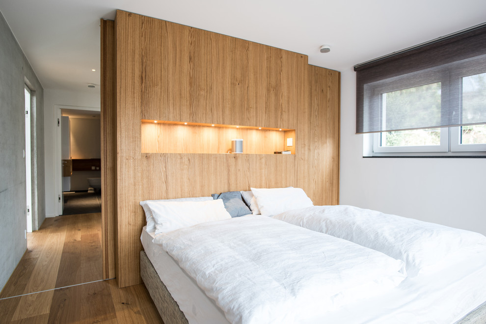 Пример оригинального дизайна: хозяйская спальня среднего размера в скандинавском стиле с белыми стенами, паркетным полом среднего тона и коричневым полом без камина