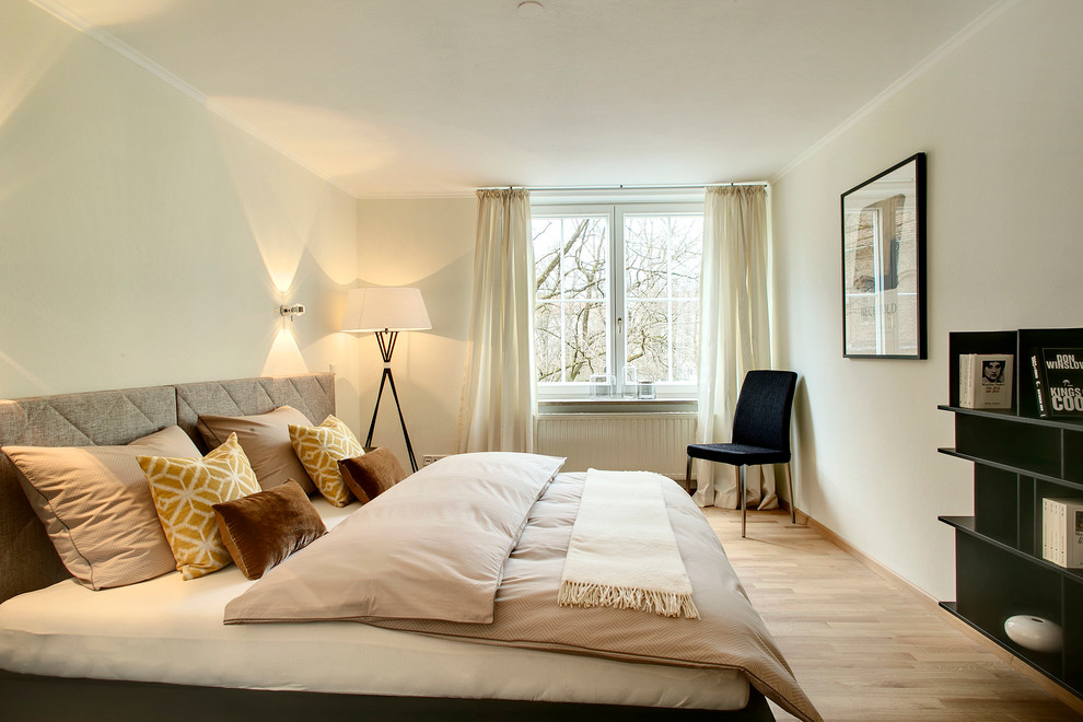 Cette photo montre une chambre parentale tendance de taille moyenne avec parquet clair et un mur beige.